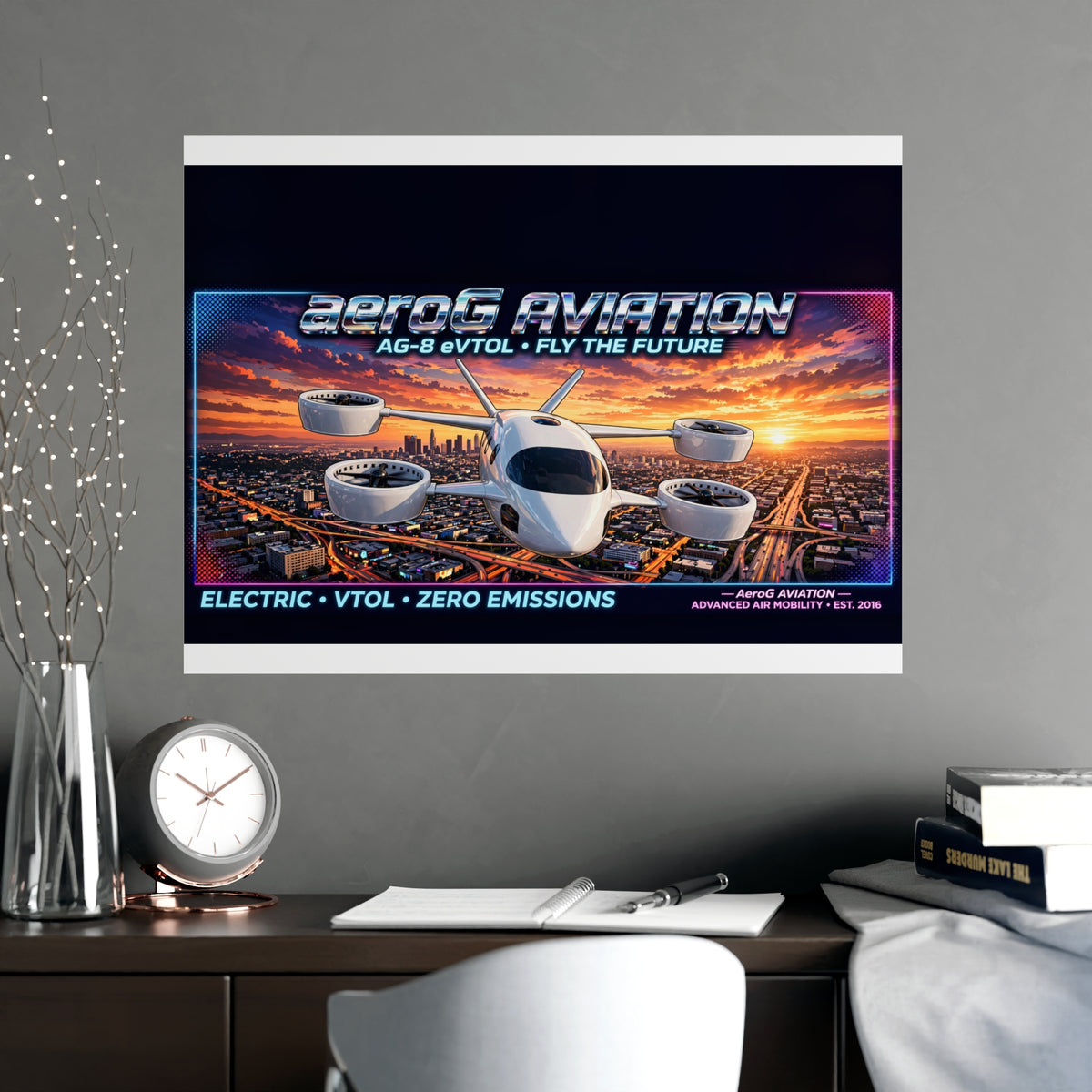 Arcade style aviation poster: LA Sunset — lifestyle mockup of the framed poster on a gray wall above a desk with a clock, books, papers, a vase of decorative branches, and a white chair, by aeroG Aviation